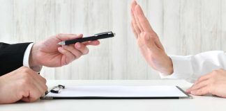 hand holding pen while another hand is held up to suggest no