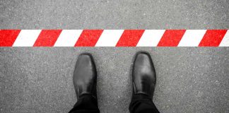 Feet on one side of a red and white striped line