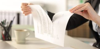Hands ripping piece of paper in half