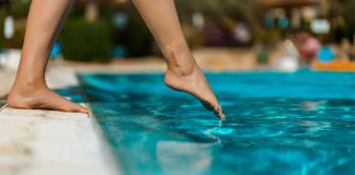 Barefoot testing the water of a swimming pool