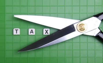 Scissors cutting around the word tax in block letters on a green background