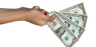 Hand holding four $1 bills