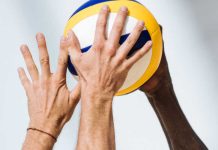 Two hands clamoring over a volleyball