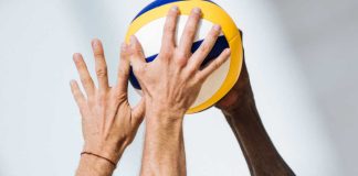 Two hands clamoring over a volleyball