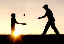 Silhouette of man throwing baseball to child with bat