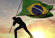Silhouette planting Brazil flag in ground