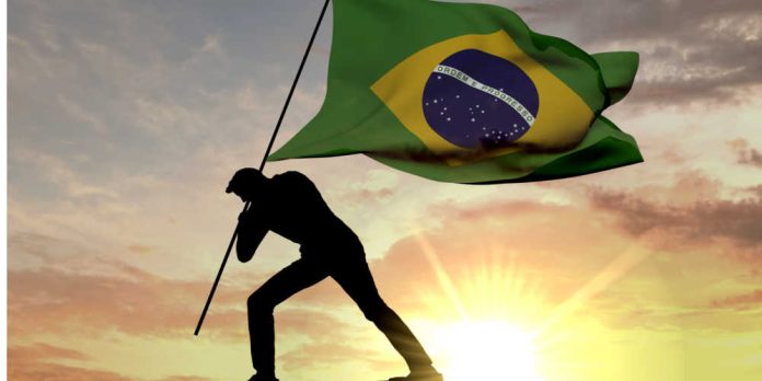 Silhouette planting Brazil flag in ground