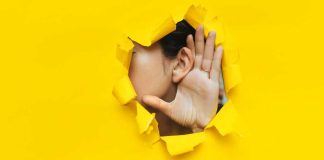 Hand and ear through hole in yellow paper