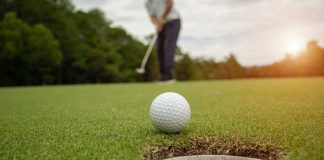Golfer putting golf ball into hole