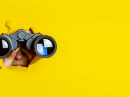 hands on binoculars yellow background