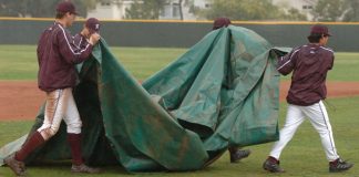 Basebal staff carrying a rain delay tarp
