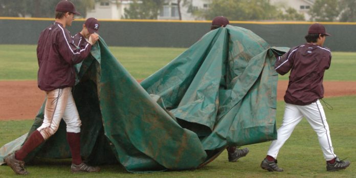Basebal staff carrying a rain delay tarp
