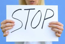 Hands holding a handwritten stop sign