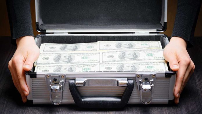 Hands holding suitcase full of money