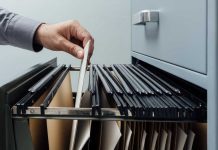 Hand putting folder in filing cabinet