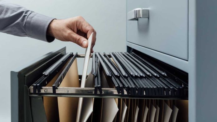 Hand putting folder in filing cabinet