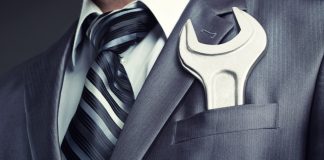A man has a spanner in his suit jacket pocket