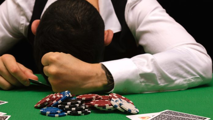 Forlorn gambles rests his head on a poker table