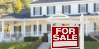 Red for sale sign with a house in the background