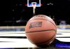 Close up of a basketball with the march madness logo on a basketball court
