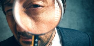 Close up of a man looking through a magnifying glass