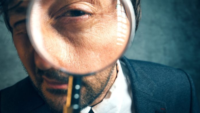 Close up of a man looking through a magnifying glass
