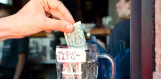 Hand putting dollar in tip jar
