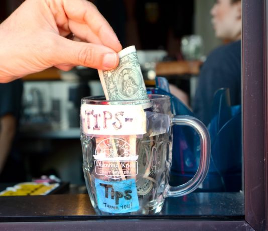 Hand putting dollar in tip jar