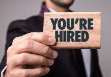 A man holds a sign saying You're Hired