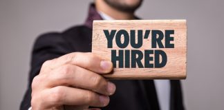 A man holds a sign saying You're Hired
