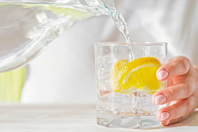 Close up of water being poured into a glass from a jug