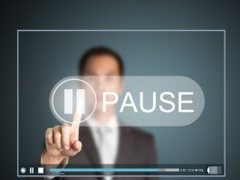Man in suit presses on a pause button