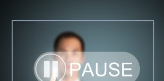 Man in suit presses on a pause button