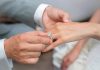Close up of a man putting an engagement ring on a woman's hand