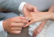 Close up of a man putting an engagement ring on a woman's hand