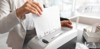 A person shredding a piece of paper, such as a license application