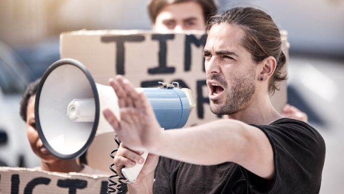 A man with a megaphone publicly denouncing something, like PENN Entertainment has done to HG Vora