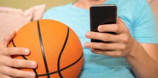 Man plays with basketball and phone as SBC Summit Americas discusses paid fantasy and sports betting