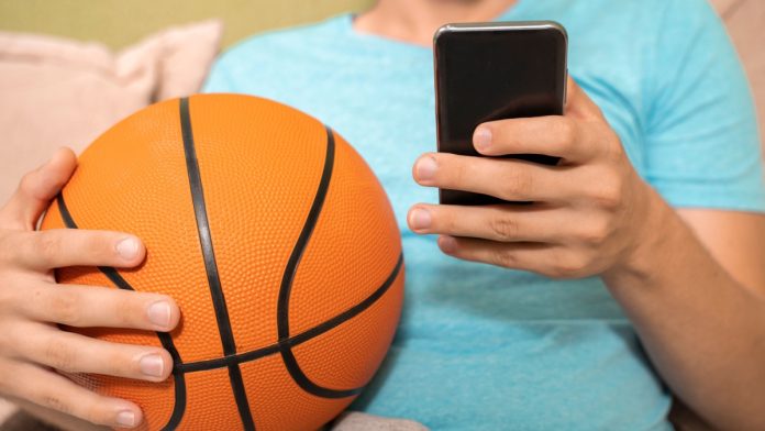 Man plays with basketball and phone as SBC Summit Americas discusses paid fantasy and sports betting