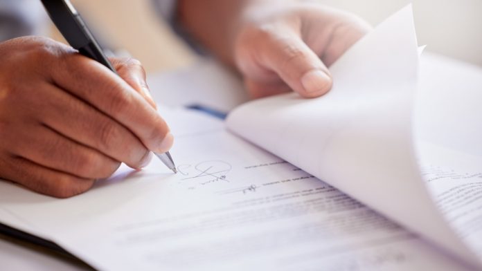 A person signs a document as Connecticut (CT) Gov. Ned Lamont signs a bill to ban sweepstakes casinos.