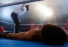 A knocked-out boxer lying on a boxing ring mat