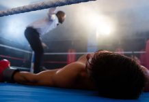 A knocked-out boxer lying on a boxing ring mat