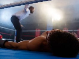 A knocked-out boxer lying on a boxing ring mat