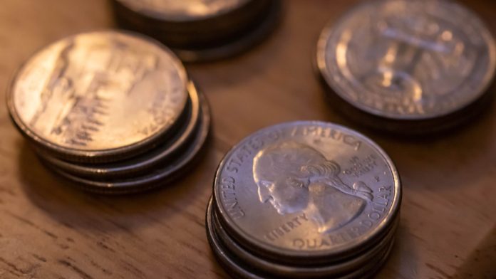 Several stacks of quarters as DraftKings plans to implement a 50 cents transaction fee on sports wagers in Illinois.