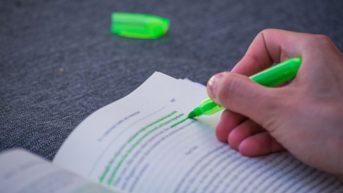 A person highlighting text in a book