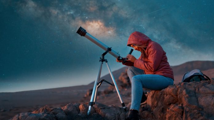 Woman looks through telescope as IGT rebrands its lottery business to Brightstar Lottery.