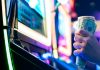 A person grasping 50-dollar bills while sat at a slot machine