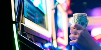 AGA hails ‘long-overdue’ change to slot tax reporting threshold A person grasping 50-dollar bills while sat at a slot machine
