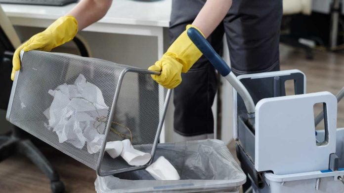 Janitor emptying office waste basket