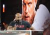 Mike Tyson speaking in front of a poster of Jake Paul